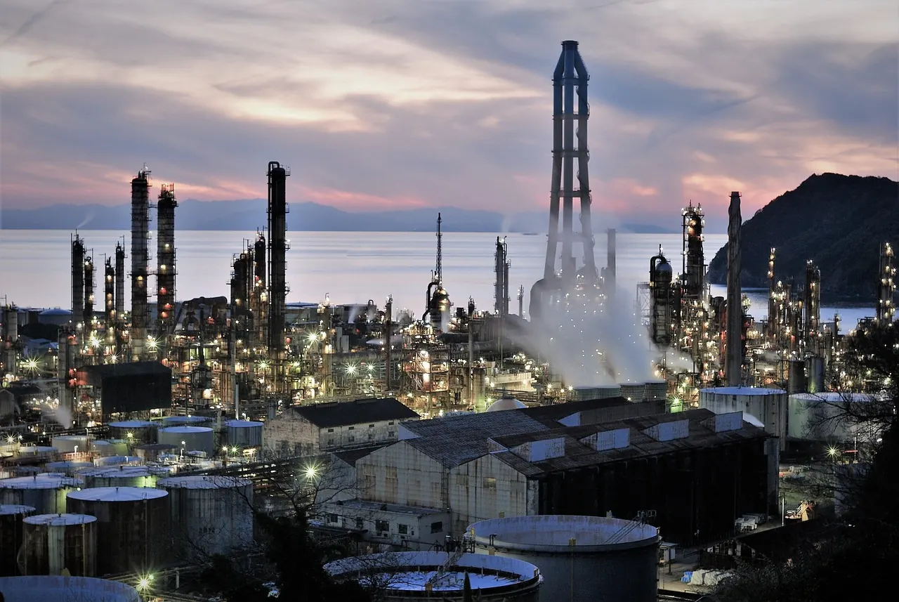 Gas processing facility lit up at dusk by the water